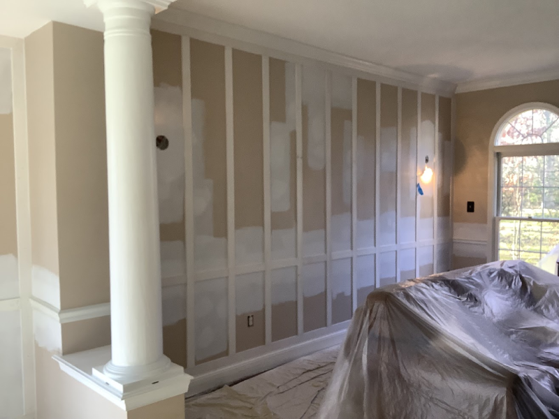 dry-painting-img Room under renovation with patches of spackle on walls, a ladder, and a stone fireplace.